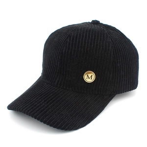 Close-up of black corduroy baseball cap featuring a golden metal M letter emblem detail