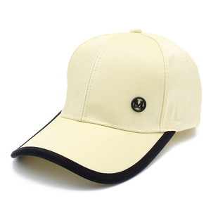 Fashionable beige baseball cap with black trim and a metal M logo on pure white background