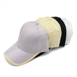 Detailed view of four satin baseball caps in purple, cream, black, and white with metal M logo