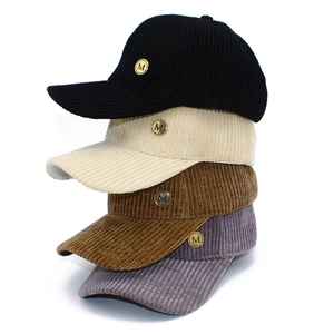 Close-up of corduroy baseball caps in four colors with metallic M logo embroidery