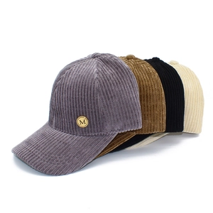 Detail of four corduroy baseball caps in purple, brown, black and beige with metal M logo