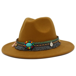 Détail d'un chapeau fedora camel avec ruban ethnique tissé, turquoise et pompons latéraux