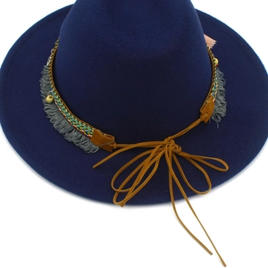Detail of navy blue felt fedora featuring ethnic woven band with grey fringe accents