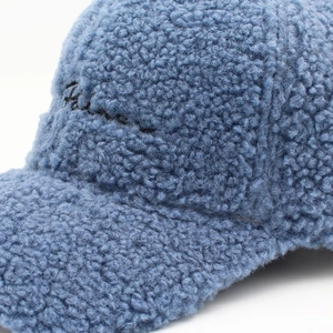 Detailaufnahme der blauen Lammwolle-Baseballkappe mit schwarzer Buchstabenbestickung