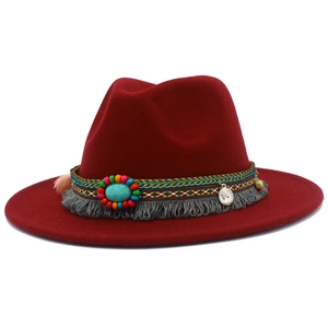 Détail d'un chapeau fedora rouge avec ruban ethnique, turquoise, perles et franges