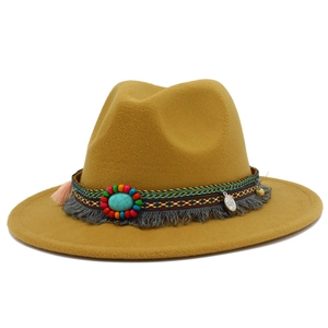 Détail du chapeau fedora western avec pierre turquoise, perles et pompons sur le bord large