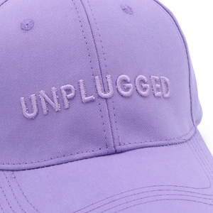 Close-up of UNPLUGGED 3D embroidery on high-quality purple cotton canvas baseball cap