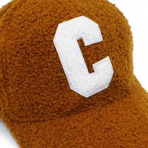 Close-up of fluffy brown lamb wool texture and white Chenille letter C patch embroidery