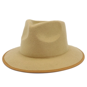 Close-up of beige wool fedora hat featuring a wide brim and brown fabric binding detail