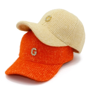Détail de la casquette en tricot avec lettre G et strass en mohair beige et orange