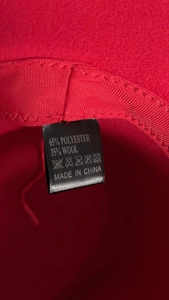 Detail view of care label showing 35% wool blend material on a red wool fedora hat