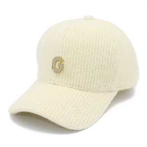 Détail d'une casquette de baseball tricotée avec lettre G en strass et maille crème