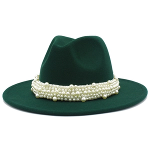 Detalle de sombrero fedora verde oscuro con cinta blanca y adornos de perlas elegantes