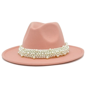 Detalle de sombrero fedora de lana rosa melocotón con decoración de perlas blancas en ala
