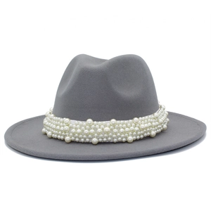 Détail de perles blanches sur un chapeau fedora gris à bord large avec texture élégante