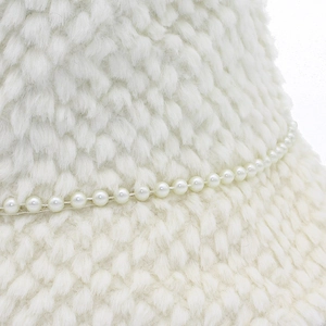 Détail d'un chapeau bob en peluche blanche avec chaîne de perles et texture douce