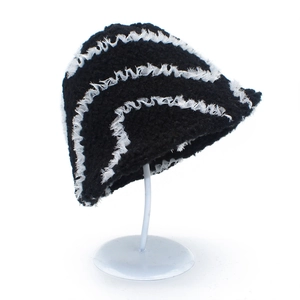 Detail eines schwarzen Strickhutes mit weißen Wellenkanten und grober Häkeltextur im Fokus