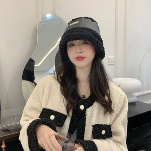 Détail d'un chapeau bob contrasté en cuir noir et polaire douce avec étiquette métallique