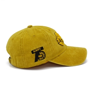 Dettaglio del cappellino in cotone giallo senape con ricamo laterale di lettere
