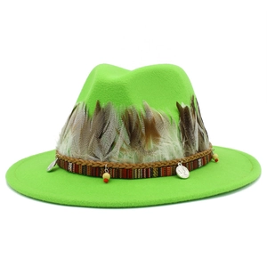 Detail of lime green fedora hat featuring ethnic ribbon, feathers and metal coin charm