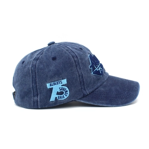 Dettaglio del ricamo sulla berretta da baseball in denim lavato blu scuro con cuciture fini