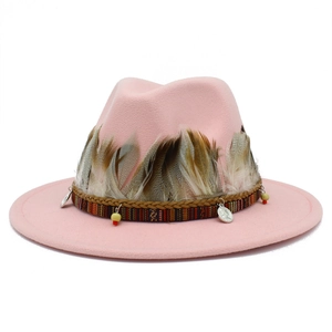 Detail of pink fedora hat featuring ethnic ribbon, natural feathers and metallic charms