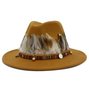 Detail of camel wool fedora hat featuring layered natural feathers and woven ethnic band