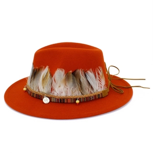 Detail of orange fedora featuring ethnic braided bands, natural feathers and metal coins