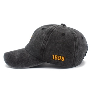 Detail view of charcoal grey washed denim cap with yellow 1999 embroidery on side