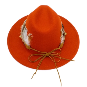 Detail of orange wide brim fedora hat featuring real feathers and braided bead band