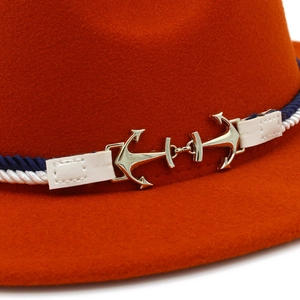 Close-up of golden anchor metal buckles and blue-white braided rope on orange wool felt hat