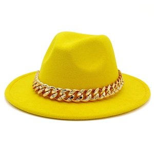 Close-up of bright yellow wool fedora hat featuring a chunky gold chain decoration