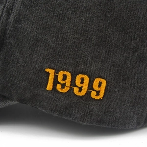Macro detail of yellow 1999 embroidery on textured charcoal cotton baseball cap fabric