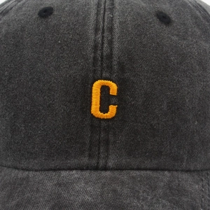 Close-up of vintage washed cotton fabric and yellow letter C embroidery on dark grey baseball cap