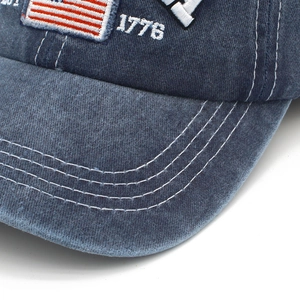 Close-up of washed denim fabric with USA flag embroidery and 1776 text on a baseball cap
