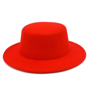 Close-up of bright red wool felt flat top hat featuring fine texture and minimalist design