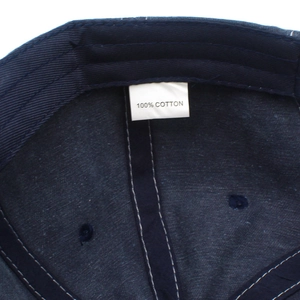 Detailed macro view of 100% cotton fabric label and white stitching inside navy baseball cap