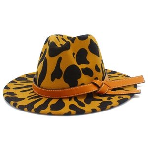 Detail of wide brim cow print fedora hat featuring a brown leather band and stitching