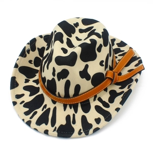 Detail of a cow print fedora hat with a brown leather strap and stylish side knot decoration