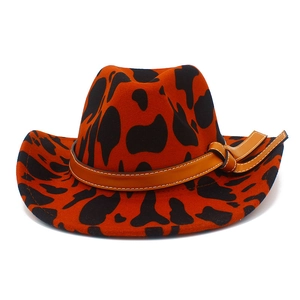 Detail of orange cow print wool hat featuring a brown leather band and side knot decor