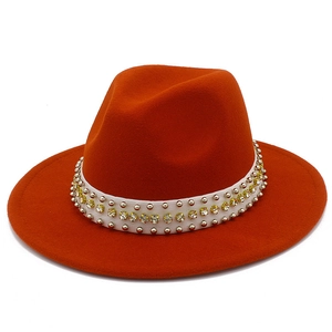 Detail of orange wool fedora featuring a white band with yellow rhinestones and silver studs