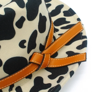 Cow print felt fedora hat with a wide brim and a bright orange leather buckle band