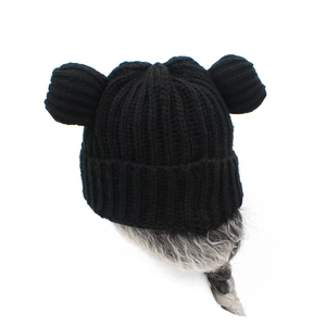 Dettaglio di cappello nero lavorato a maglia con orecchie d'orso e lunghe trecce grigie