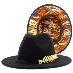 Close-up of black wool fedora with gold feather pin and orange tiger print lining