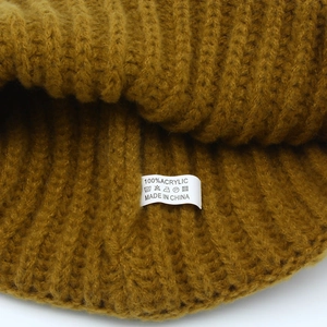 Dettaglio della maglia spessa giallo zenzero e dell'etichetta del materiale 100% acrilico