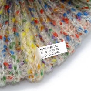Detailed macro view of rainbow knitted winter hat fabric and 100% acrylic care label