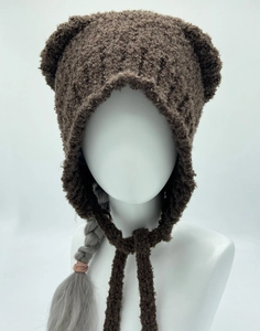 Detail van bruine pluche berenoormuts met dikke fleece textuur en koordsluiting