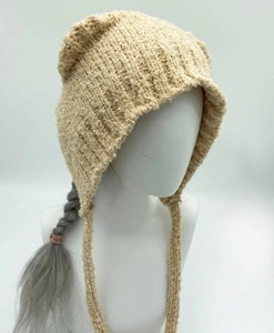 Detail van gebreide muts met schattige berenoren en veters in beige pluche garen
