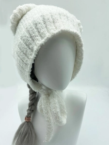 Detailopname van witte gebreide muts met zachte pluche textuur, oorkleppen en grote pompon
