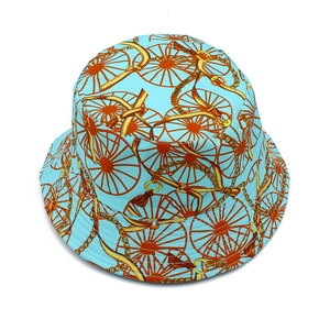 Detail eines hellblauen Fischerhutes mit orangefarbenem Kutschenmuster und Stofftextur